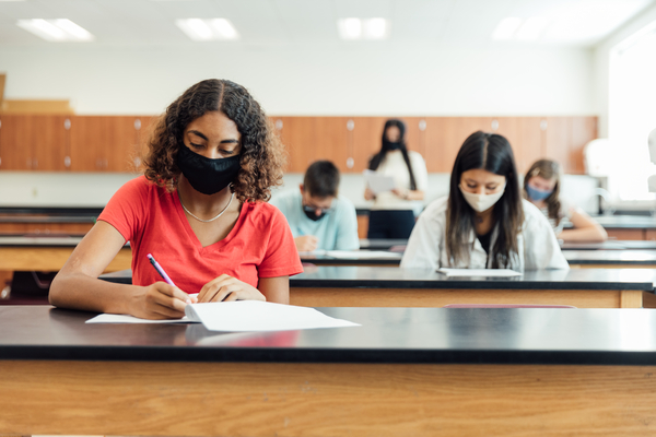 High school students and teenagers go back to school in the classroom at their high school. They are required to wear face masks and practice social distancing during the COVID-19 pandemic.